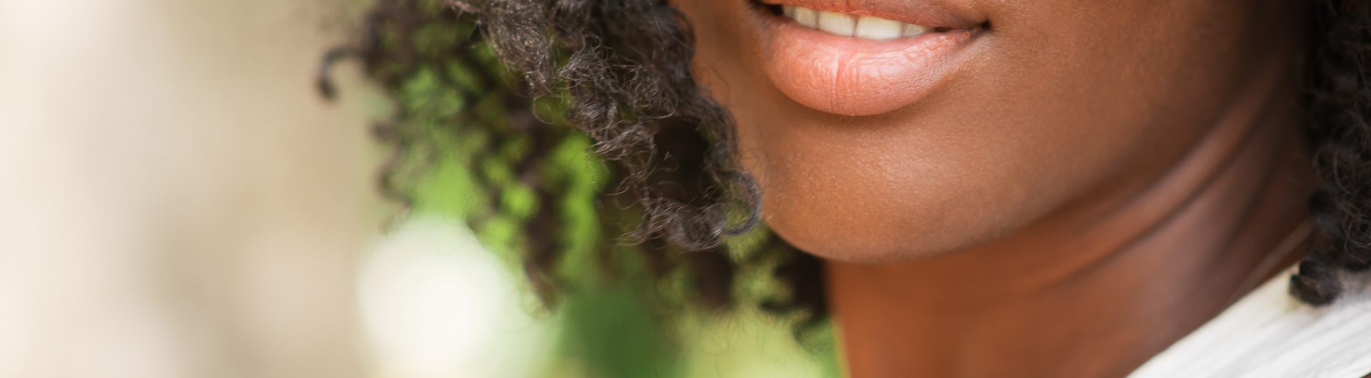 Cropped view of smiling young attractive African American woman outdoors